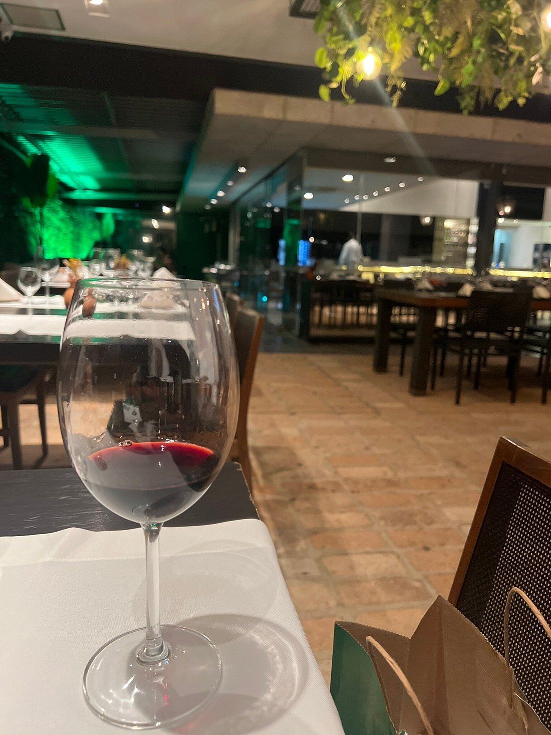 Taça de vinho tinto com o salão iluminado ao fundo